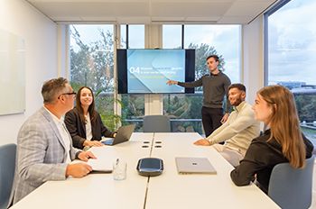 Teammeeting met presentatie over klantreisanalyse en digitale marketingstrategie